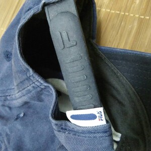 May include: A navy blue baseball cap with a black adjustable strap and a white Fila logo.