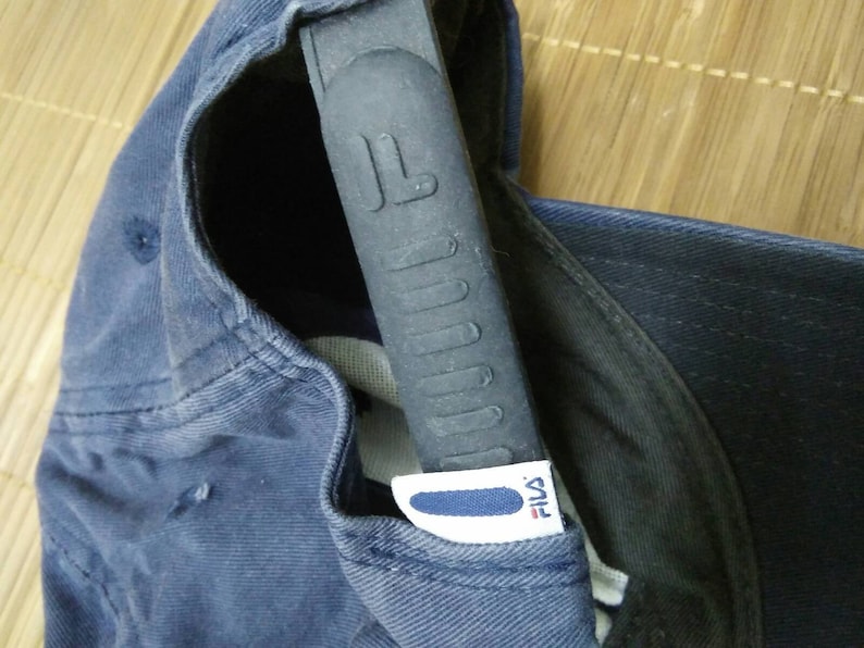 May include: A navy blue baseball cap with a black adjustable strap and a white Fila logo.