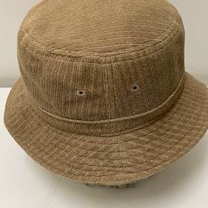 May include: A brown corduroy bucket hat. The hat has a wide brim and a flat crown.