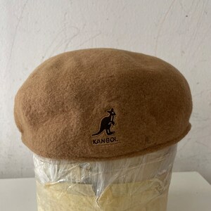 以下が含まれることがあります： カンゴールの茶色のウールベレー帽。茶色のカンガルーのロゴ入り