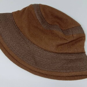 May include: A brown knitted bucket hat with a darker brown brim.