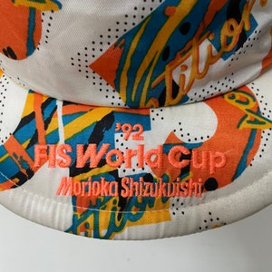 May include: White baseball cap with a colorful geometric pattern and the text "FIS World Cup Morioka Shizukuishi 1992" embroidered in orange.
