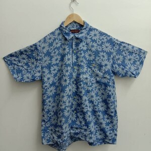 Op de afbeelding: Een blauw, kort mouwig overhemd met knopen en een wit bloemenpatroon.