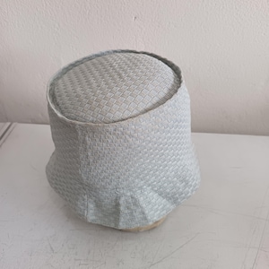 May include: A light gray bucket hat featuring a textured, woven basket-weave pattern throughout the crown and the brim. The hat has a structured, rounded top and a slightly flared, flexible brim, showcasing a consistent light gray color tone.