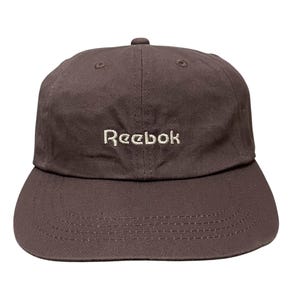 May include: A brown baseball cap with a white embroidered Reebok logo.