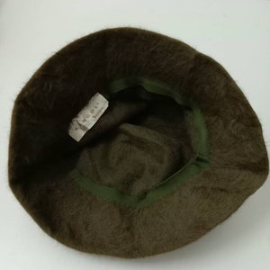 May include: A brown fuzzy bucket hat with a green inner band. The hat has a label that reads "Kangol.  Berlino."