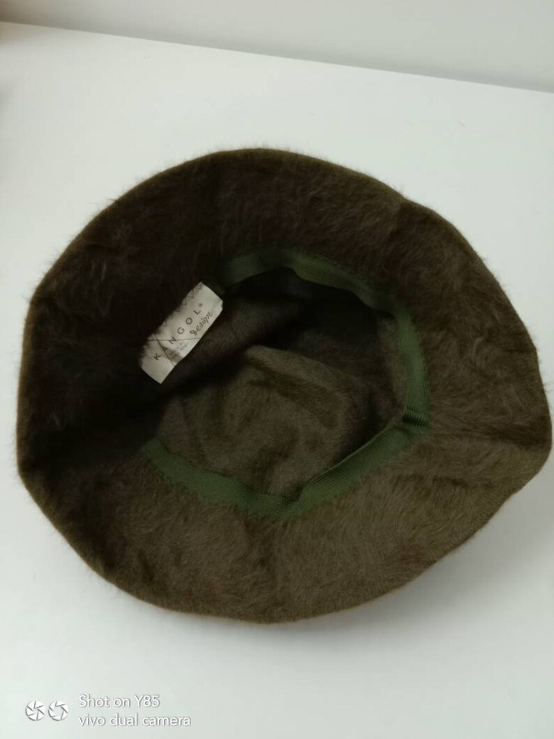 May include: A brown fuzzy bucket hat with a green inner band. The hat has a label that reads "Kangol.  Berlino."
