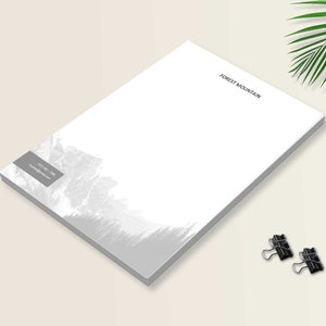 May include: A stack of white letterhead paper featuring the text FOREST MOUNTAIN in black at the top right and a gray mountain landscape graphic at the bottom left with contact information in a gray box. Two black metal binder clips are included.