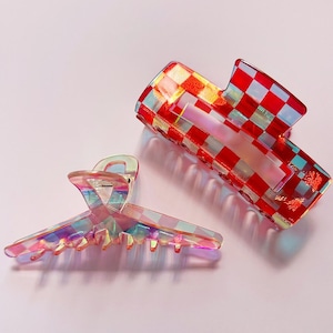 May include: Two plastic hair clips. One is red and white checked, the other is iridescent.