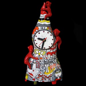 May include: A ceramic clock tower with a white face and black hands. The tower is decorated with red, black, white and yellow paint. The tower is surrounded by small red figures.