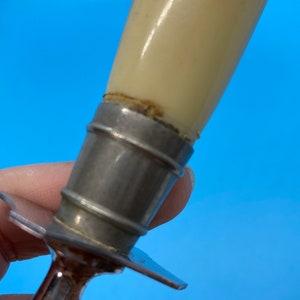 May include: Close-up of a vintage knife with a cream-colored handle and a silver metal bolster. The handle appears to be made of a smooth, glossy material. The blade is visible, with a silver metal finish.