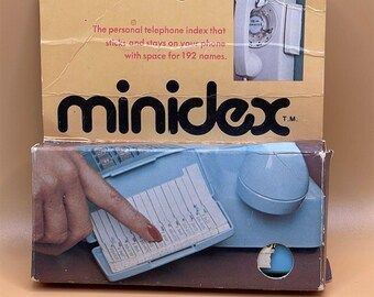 May include: A blue and white phone index card holder with the text "minidex T.M." on the front. The holder is designed to stick to a phone and has space for 192 names.
