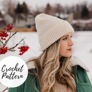 Könnte beinhalten: Nahaufnahme einer Frau, die eine weiße Häkelmütze trägt. Die Mütze hat ein strukturiertes Stichmuster und einen umgeschlagenen Rand. Die Frau hat lange blonde Haare und trägt eine grüne Jacke.