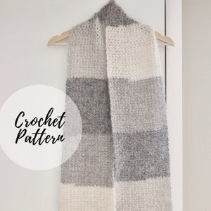 May include: A crocheted scarf with a striped pattern in white and grey. The scarf is hanging on a wooden hanger. The text "Crochet Pattern" is written in a circle on the left side of the image.