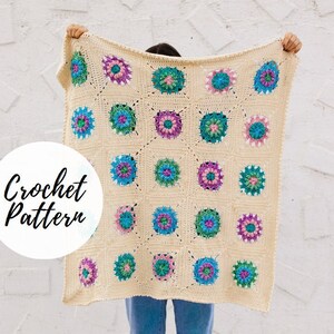 May include: A crocheted blanket with a cream background and colorful floral motifs. The blanket is made with a granny square pattern and features shades of pink, blue, and green.