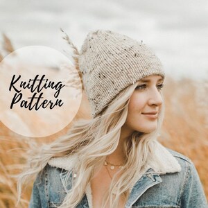 May include: A woman wearing a beige knitted beanie with a speckled pattern. She is wearing a denim jacket and has long blonde hair.