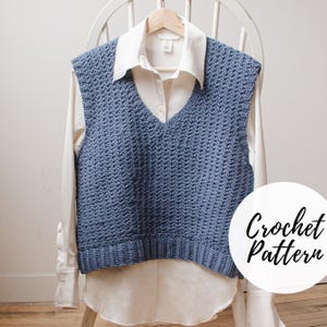 May include: A blue crocheted vest with a V-neckline. The vest is displayed on a white shirt and a white chair. The text "Crochet Pattern" is visible in the lower right corner of the image.