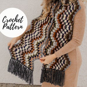 May include: A crochet scarf with a granny square pattern in shades of brown, gray, white, green, and black. The scarf has a fringe on the ends.