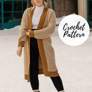May include: A long, open-front crochet cardigan in a houndstooth pattern of cream and brown. The cardigan has a solid brown border and trim. The text "Crochet Pattern" is in a white circle. The cardigan is worn over a white turtleneck and black leggings.