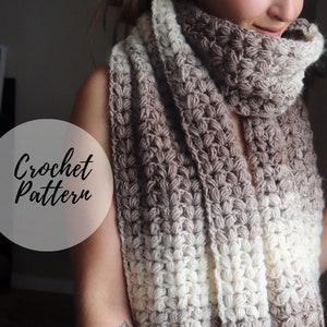 May include: A crochet scarf with a gradient of brown and white yarn. The scarf is folded and draped around a person's neck. The text "Crochet Pattern" is written in white on a grey circle.