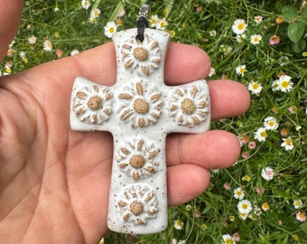 May include: White ceramic cross with a floral design. The cross is decorated with raised flower shapes in a light brown color.