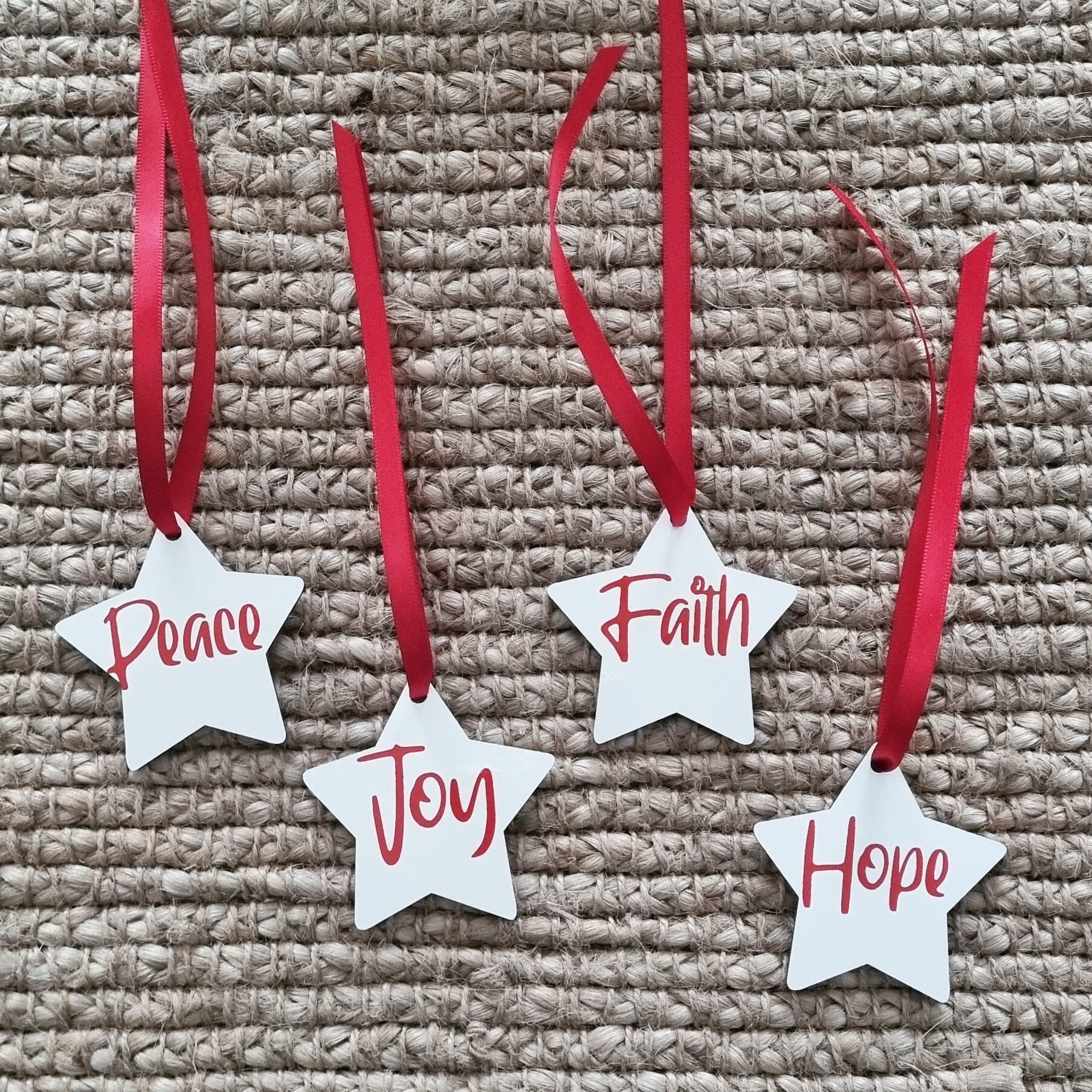 Set of 4 Christmas star decorations, Hope, Peace, Joy, Faith, white stars with red lettering hanging from red ribbon
