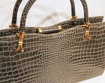 May include: A gray crocodile embossed leather handbag with gold-tone hardware and double top handles.