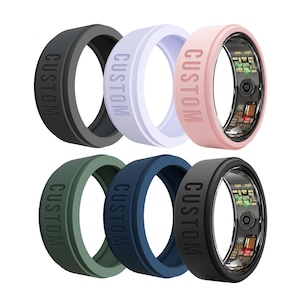 May include: A collection of six silicone ring covers in black, light purple, light pink, olive green, navy blue, and dark gray. Each band features the word CUSTOM embossed on the outer surface. Some rings show internal electronic components.