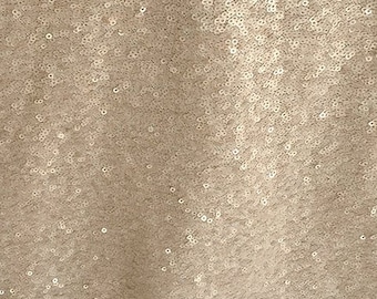 May include: Close-up of a fabric covered in small, round, champagne-colored sequins. The sequins are densely packed, creating a shimmering, textured surface. The overall effect is one of luxury and sparkle, suitable for apparel or decorative projects.