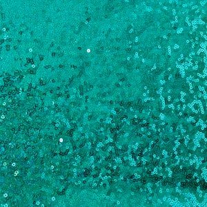 Könnte beinhalten: Nahaufnahme eines türkisfarbenen Paillettenstoffs. Der Stoff ist dicht mit kleinen, runden Pailletten bedeckt, die das Licht einfangen und einen schimmernden Effekt erzeugen. Die Pailletten haben eine leuchtende türkisfarbene Farbe, und die Gesamtstruktur ist glatt und reflektierend.