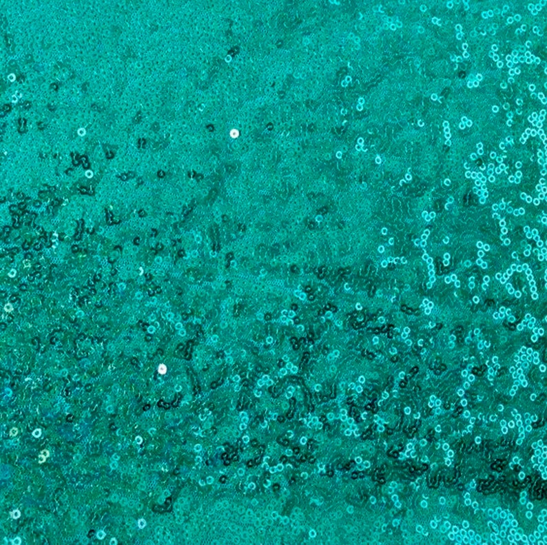 以下が含まれることがあります： ティール色のスパンコール生地のクローズアップ。生地は、光を捉え、キラキラとした効果を生み出す、小さくて丸いスパンコールで密に覆われています。スパンコールは鮮やかなティール色で、全体の質感は滑らかで反射性があります。