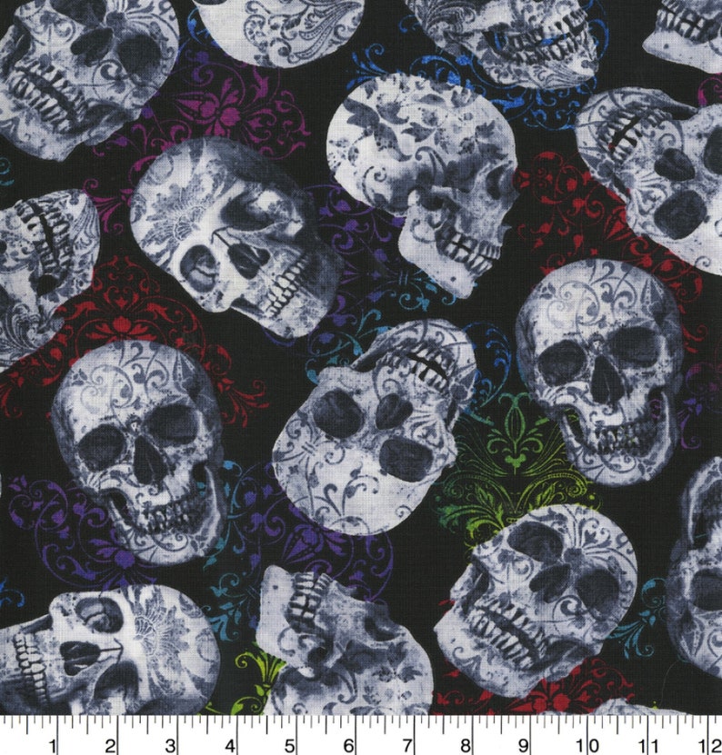 May include: Black fabric with a repeating pattern of white skulls. The skulls are detailed with floral designs. Colorful, ornate flourishes in red, purple, blue, and green are scattered throughout the design. The fabric is suitable for Halloween or gothic-themed projects.