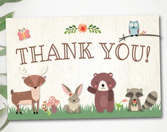 May include: Thank you card with a woodland theme. The card features a deer, a bear, a rabbit, a raccoon, and an owl. The card is on a woodgrain background with a green border.
