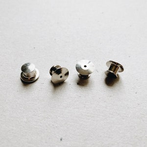 May include: Four silver metal pin back closures for crafts and jewelry making.