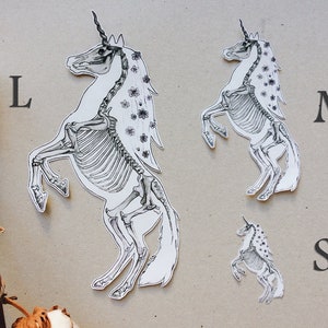 May include: Three black and white unicorn skeleton stickers in different sizes, labeled L, M, and S.