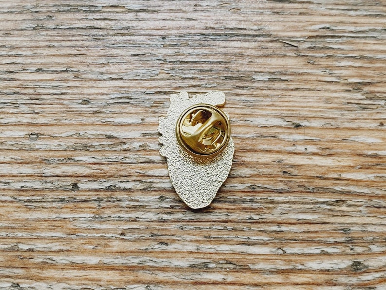 K&ouml;nnte beinhalten: Goldfarbener anatomischer Herz-Pin mit detailliertem Design. Die R&uuml;ckseite des Pins hat eine Standard-Sicherheitsnadel.