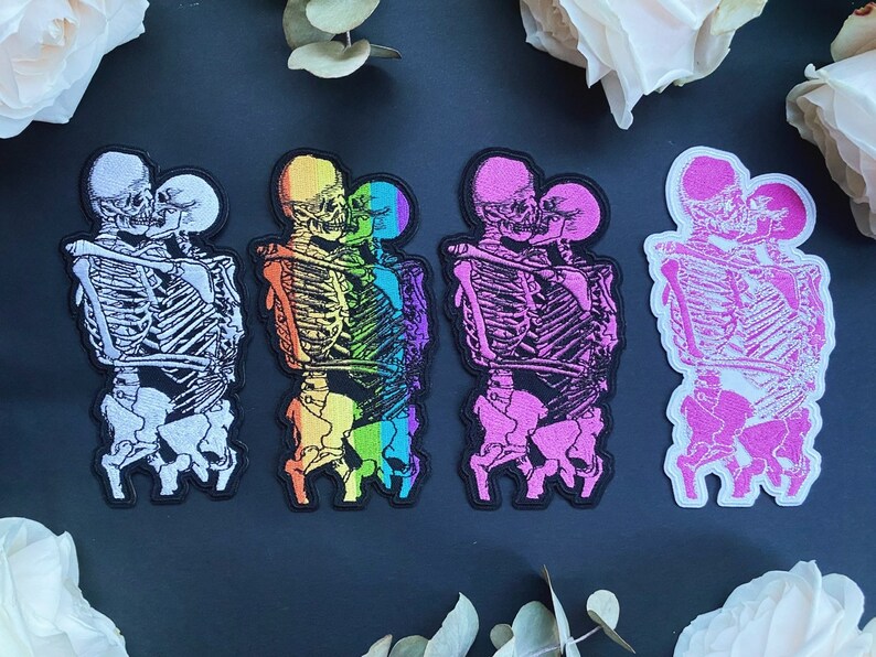 Puede incluir: Conjunto de cinco parches para planchar que representan esqueletos en un abrazo. Los parches son de varios colores, incluyendo blanco, arco&iacute;ris, rosa y negro.