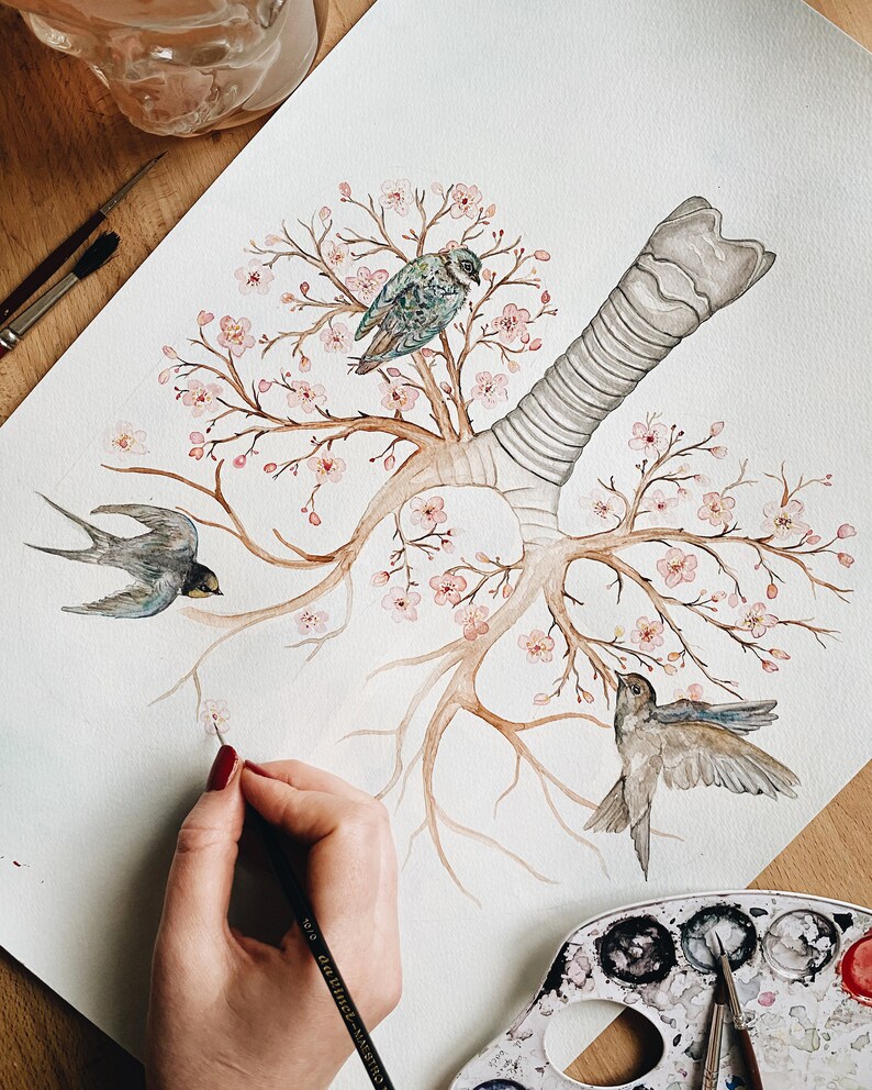 May include: Watercolor painting of a stylized human lung with branches of a cherry blossom tree growing from it. Three small birds are perched on the branches. The painting is on a white background and is being worked on by an artist.