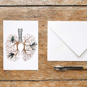 May include: A white card with a drawing of a human lung with pink flowers and birds on the branches. The card is blank and ready for a message.