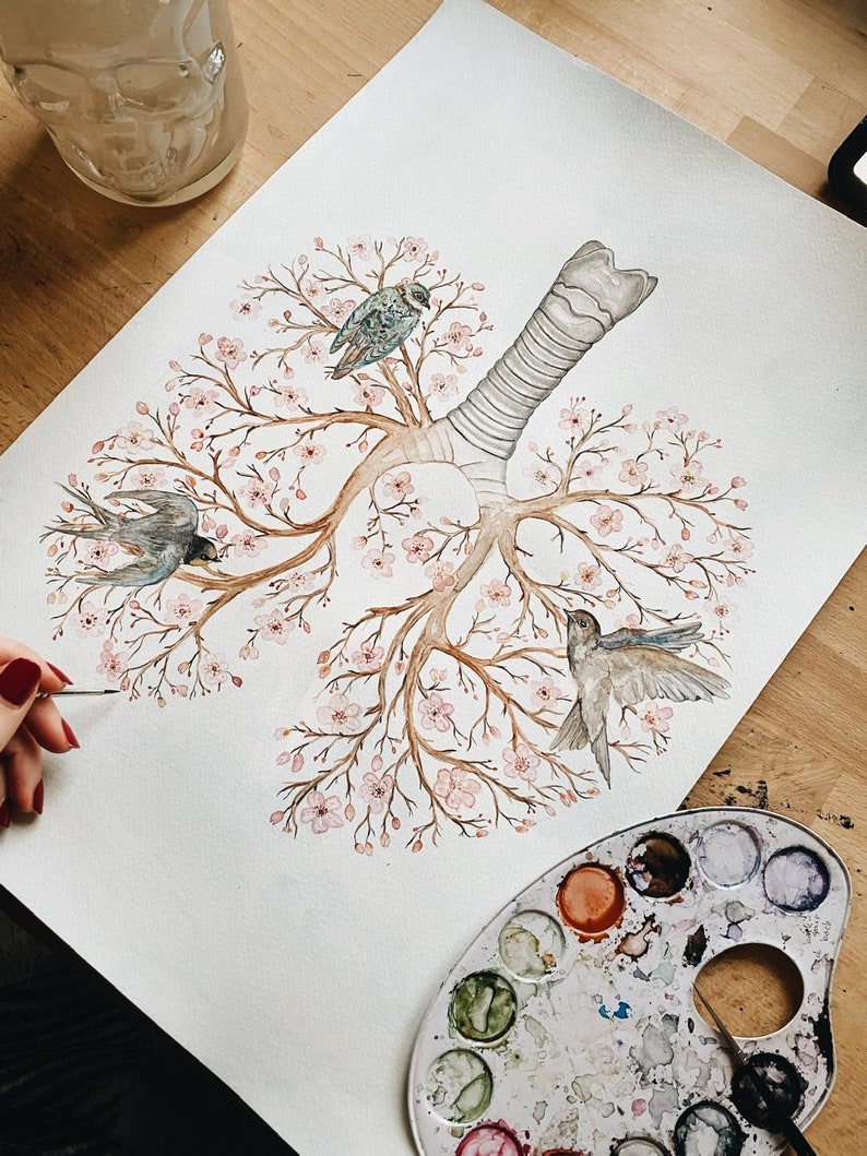 May include: Watercolor painting of a tree with pink flowers and three birds. The tree is shaped like a human lung. The painting is on a white background and is being worked on by an artist.