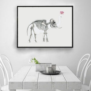 May include: A black framed print of a white elephant skeleton with a pink lotus flower above its head. The print is hanging on a white wall above a white table with two white chairs.