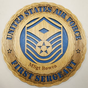 May include: A wooden plaque with a blue and brown United States Air Force First Sergeant insignia. The plaque features the text "United States Air Force First Sergeant" and "MSgt Bowen".