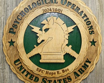 May include: Wooden plaque with the words "PSYCHOLOGICAL OPERATIONS UNITED STATES ARMY" in a circular design. The center features a horse head with lightning bolts and the date 2024/10/01. The name "SFC Hope E. Bos" is also included.