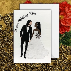 An interracial wedding card with a white groom and a black bride. The groom is wearing a black tuxedo and the bride is wearing a white a-line dress. the groom has shoulder length hair and the bride has long straight hair. The text on the card reads 'On your Wedding Day'.