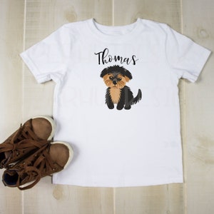 May include: White t-shirt with a black and brown Yorkshire Terrier cartoon and the name "Thomas" printed in black.