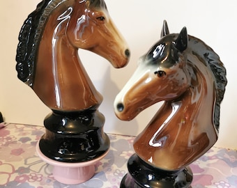 Pode incluir: Duas estatuetas de cerâmica de cabeça de cavalo com esmalte preto e marrom. As cabeças de cavalo são montadas em bases pretas com bases rosa e pretas.