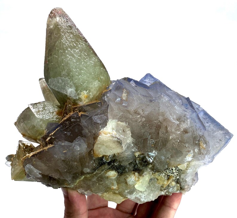 Puede incluir: Un grupo de cristales naturales en tonos verdes, azules y transparentes. Los cristales tienen una superficie rugosa y texturizada y est&aacute;n dispuestos en una formaci&oacute;n en capas. La apariencia general es la de una geoda o un esp&eacute;cimen mineral.