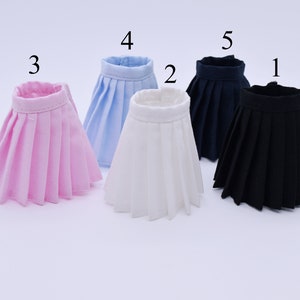 May include: Five pleated skirts in different colors: pink, light blue, white, navy blue, and black. The skirts are arranged in a row from left to right, with the pink skirt on the left and the black skirt on the right.