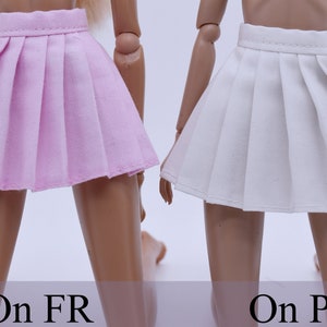 May include: Two pleated skirts, one pink and one white, are shown on doll-sized mannequins. The skirts are both short and have a simple design.
