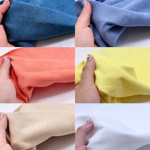 May include: Close-up of five fabric swatches in different colors: blue, orange, yellow, beige, and white. The fabric has a soft, suede-like texture.